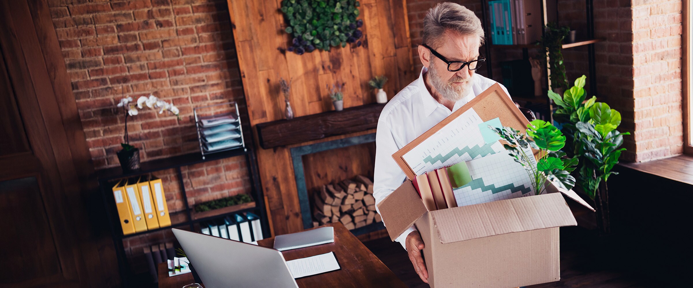 Photo of man with his work items in a box leaving an office.