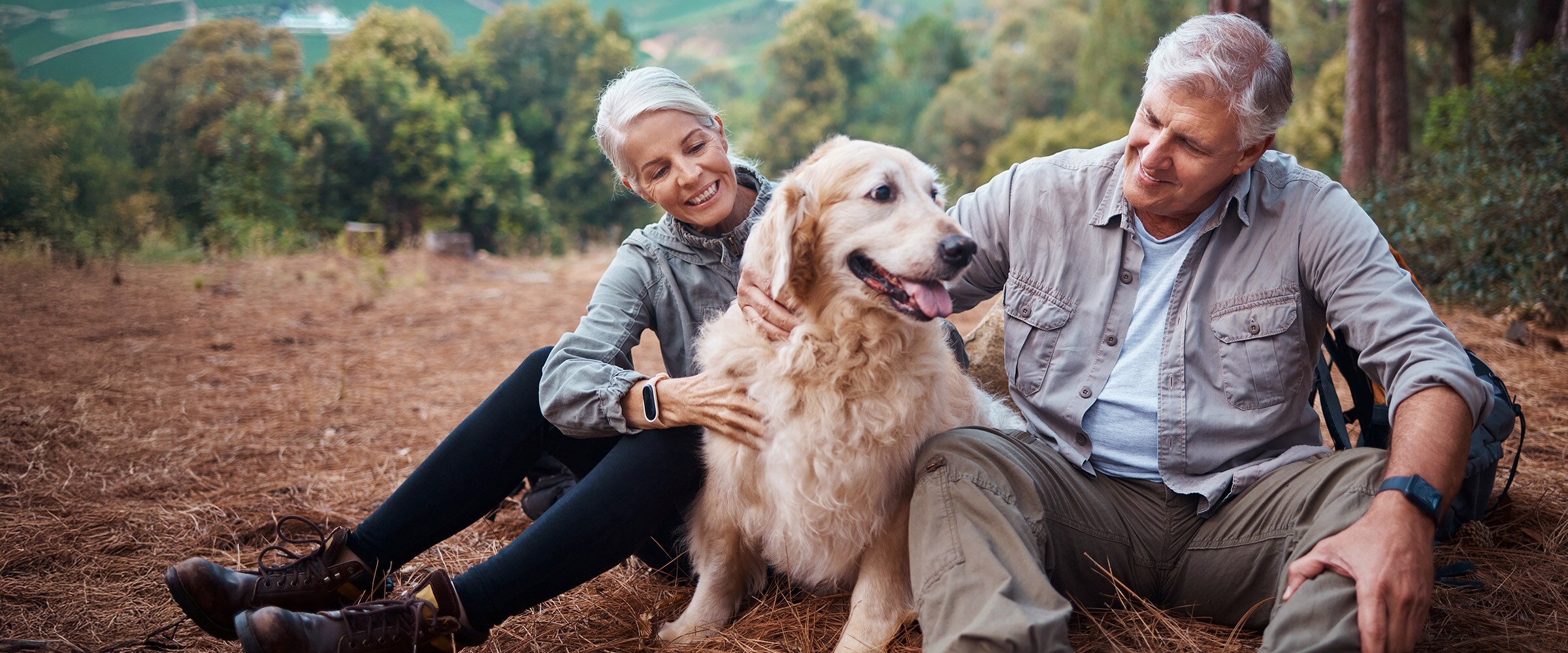 Photo of older couple sitting under a tree with a dog.