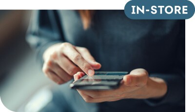 A man sitting in the waiting room of a business looks at his tablet.  The screen shows a webpage to apply online for Synchrony credit at the business.