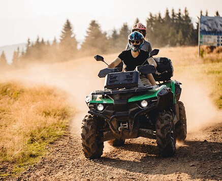 Casually dressed male pointing to a tablet in his hand, while his female coworker next to him, at her workstation, smiles and looks at the tablet as well.
