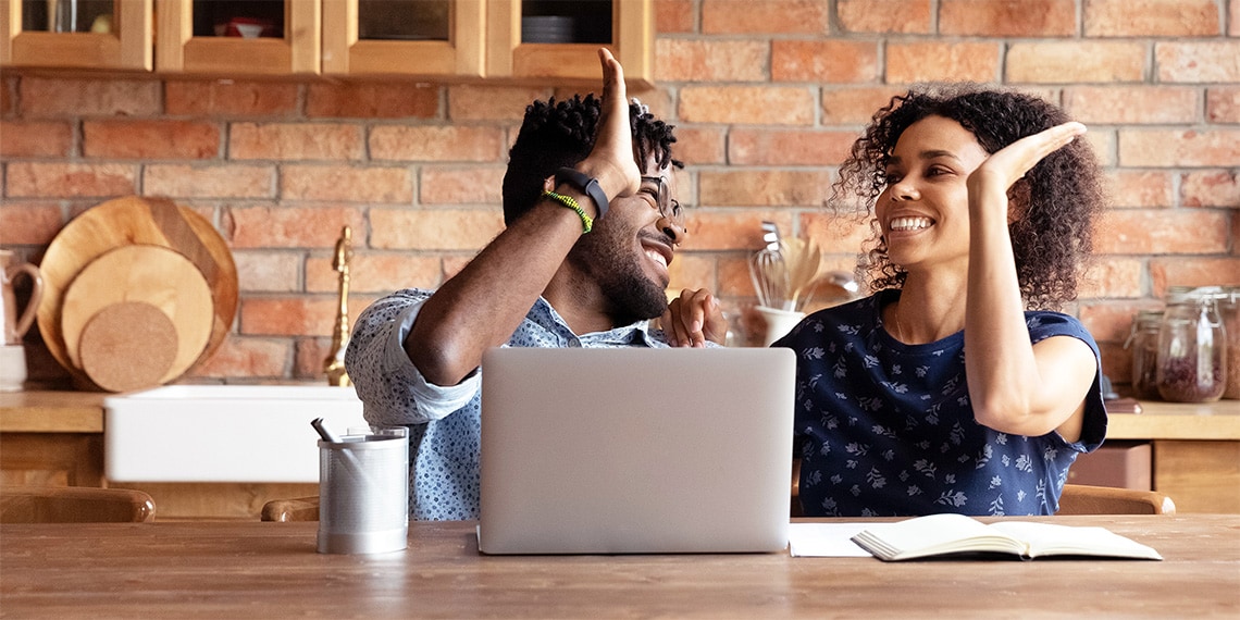 Photo of couple at table with hands raised giving each other high fives.