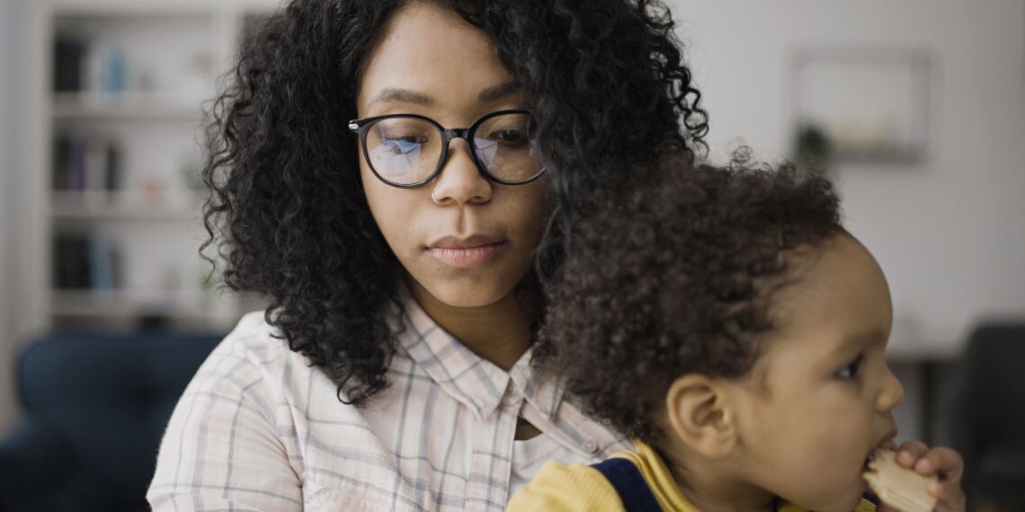 Photo of mom holding her child as she works on her computer.