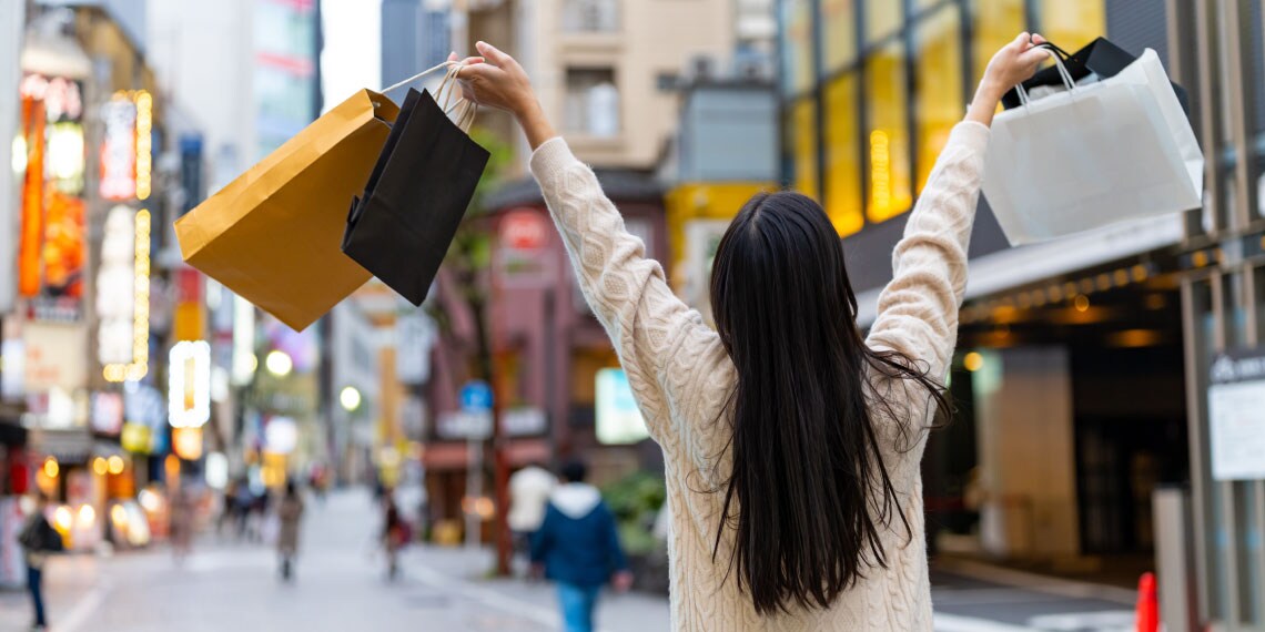 Photo of woman on street holding up shopping bags in each hand.